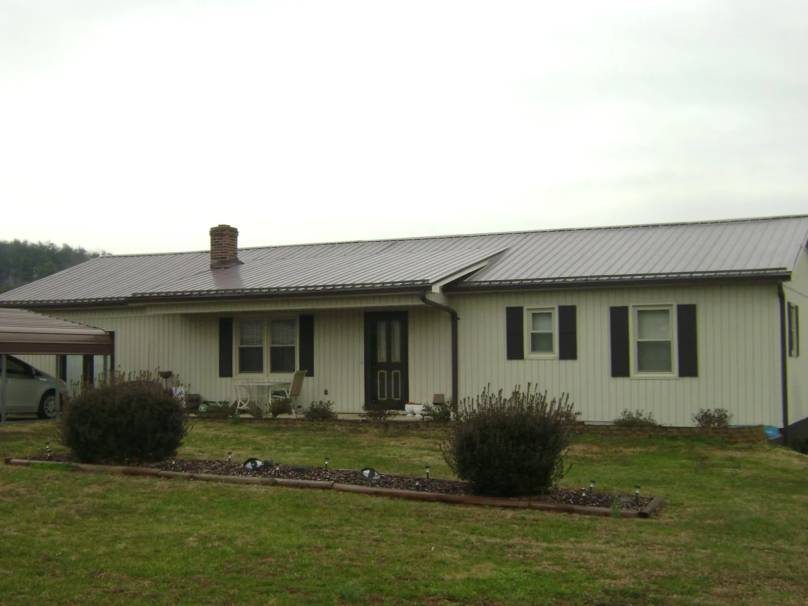 Brown metal roof on a cream sided ranch home with a brick chimney in Elizabethtown